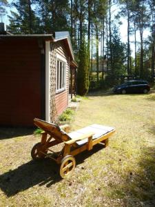 um carrinho de madeira sentado num quintal ao lado de um barracão em Ferienhaus in Yngsjö wenige Schritte zum Meer em Yngsjö