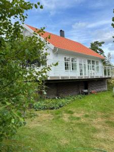 een wit huis met een oranje dak en een tuin bij Haus mit lichtdurchflutetem Wohnbereich auf einer kleinen Insel in Strömstad