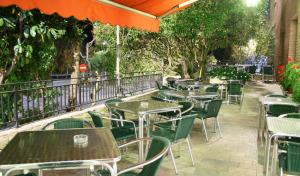 an outdoor restaurant with tables and chairs and trees at Hotel Valcarce Camino de Santiago in La Portela de Valcarce