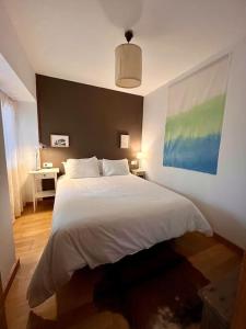 um quarto com uma cama branca e uma pintura na parede em Casa María da Reza em Ribadavia