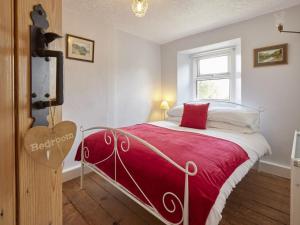 a bedroom with a bed with a red blanket and a window at 3 Bed in Wasdale SZ205 in Santon Bridge