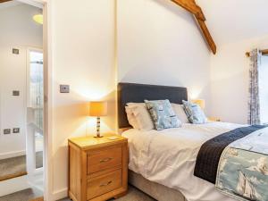 um quarto com uma cama e uma mesa de cabeceira com um candeeiro em 2 Bed in Fowey 86873 em Saint Veep