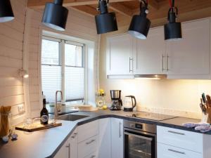 a kitchen with white cabinets and black pendant lights at Nordkugel - Kugelhaus am See in Penzlin