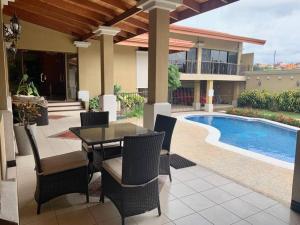 un patio avec une table et des chaises à côté d'une piscine dans l'établissement Luxury House near to Juan Sant. Airport, Alajuela., à Alajuela