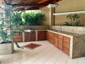 a large kitchen with wooden cabinets and plants at Luxury House near to Juan Sant. Airport, Alajuela. in Alajuela City