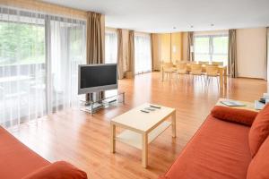 a living room with a couch and a tv and a table at Moderne Ferienwohnung in Gargellen mit 3 Schlafzimmern und Infrarotkabine in Sankt Gallenkirch