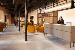 a woman sitting at a counter in a room with yellow chairs at Hotel Indigo - Dundee, an IHG Hotel in Dundee