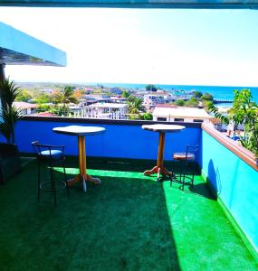 2 mesas en un balcón con vistas al océano en Hotel Los Algarrobos, en Puerto Baquerizo Moreno