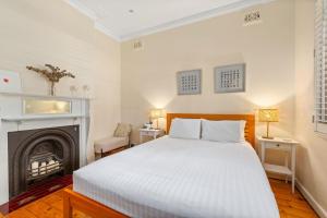 a bedroom with a white bed and a fireplace at Heritage Charm in Manly's Sun-Drenched Paradise in Sydney