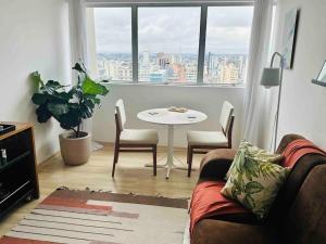 uma sala de estar com um sofá, uma mesa e uma janela em A melhor opção no centro com vista panorâmica em Curitiba