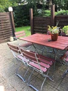 a red picnic table with two chairs and a potted plant at Ferienhaus Knorburg im Herzen Nordfrieslands in Enge-Sande