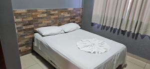 Una cama con sábanas blancas y almohadas. en Hotel Itavera II, en Presidente Prudente