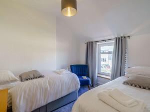 um quarto com 2 camas e uma cadeira azul em 2 Bed in Glenridding 85425 em Glenridding