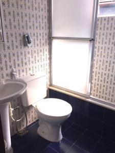 y baño con aseo blanco y lavamanos. en Versall Homestead en Petrópolis