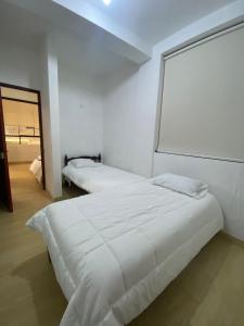 a white bedroom with two beds and a window at Mini apartamento en Ayacucho in Ayacucho