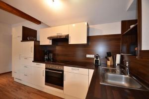 a kitchen with white cabinets and a stainless steel sink at Modernes Appartement vor herrlicher Gebirgskulisse mit zwei Balkonen und Kamin in Umhausen