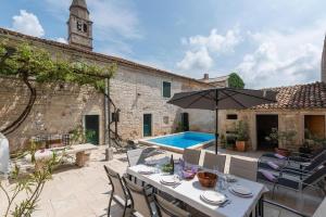 a patio with a table and an umbrella and a pool at Charmantes Ferienhaus in Svetvinčenat mit Privatem Pool in Svetvinčenat