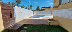 a swimming pool with a wooden deck next to a wall at COSTE0100 - Residencial Luz das Acácias in Salvador