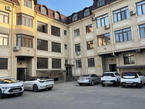 un grupo de coches estacionados frente a un gran edificio en Modern Lux en Samarcanda