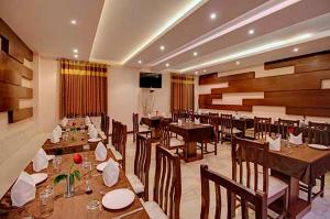 a restaurant with wooden tables and chairs and a television at Hotel Rudra Vilas in Agra