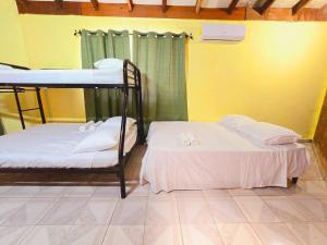 2 literas en una habitación con una pared amarilla en Años Dorados - Casa rústica a 200 mts de la Playa Punta Chame, en Punta Chame