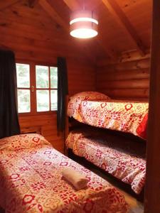 a bedroom with two beds in a log cabin at cabaña junto al arroyo in San Martín de los Andes