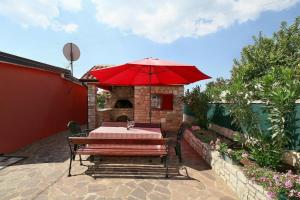 a table with a red umbrella on a patio at Ferienhaus mit Pool und zahlreichen Annehmlichkeiten für einen entspannten Familienurlaub in Buje