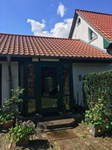 una casa con techo rojo y algunas flores en Gästezimmer mit Terrasse, en Zehdenick