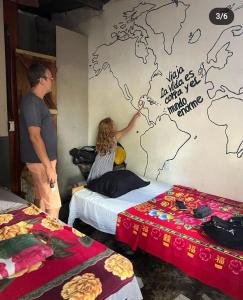a man and a woman painting a map on a wall at coraizone hostel in Cobán