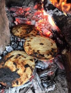 three pizzas are cooking on a grill with flames at coraizone hostel in Cobán