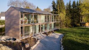 a large house with glass windows on a lawn at Sportives Ökologisches Lifestyle-Ferienhaus mit großem Außenpool, Sauna und Fitnessbereich in Donaueschingen