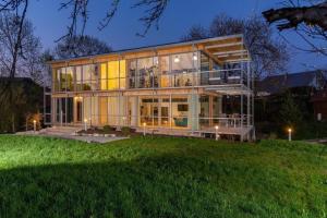 una gran casa de cristal en una colina por la noche en Sportives Ökologisches Lifestyle-Ferienhaus mit großem Außenpool, Sauna und Fitnessbereich, en Donaueschingen