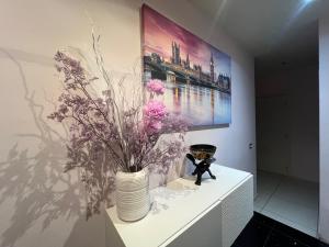 un jarrón con flores en una mesa blanca con una pintura en Stylish flat in San Giovanni Lupatoto, en San Giovanni Lupatoto