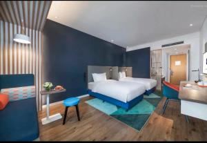 a bedroom with a white bed and a blue wall at Holiday Inn Express Qingdao Chengyang Central, an IHG Hotel in Qingdao