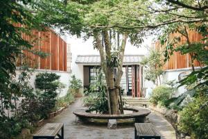 a courtyard with a tree and two benches at Central Hotel Imari in Imari