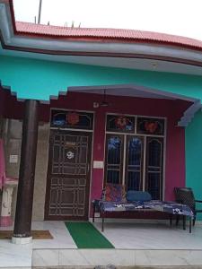 a purple and green building with a bench in front at POP Pinki Homestay in Arli