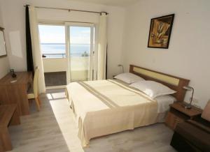 1 dormitorio con 1 cama y puerta a un balcón en Ferienhaus am Meer - kostenloses Aufladen von Elektrofahrzeugen, en Rtina