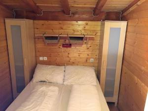 a small bed in a room with wooden walls at Ferienhaus in Porlezza mit Terrasse und gemeinsamem Pool in Porlezza