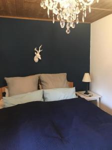 a bedroom with a blue bed and a chandelier at Hundefreundliches Ferienhaus in Zandt mit Terrasse, Grill und Garten in Zandt