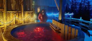 a woman standing next to a hot tub with red water at Die Berghexn, am Klippitztörl in Bad Sankt Leonhard im Lavanttal