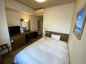 a hotel room with a bed and a desk and a mirror at Hotel Route-Inn Hanamaki in Hanamaki