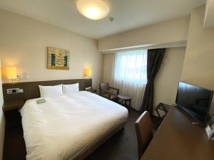 a hotel room with a bed and a television at Hotel Route-Inn Hanamaki in Hanamaki