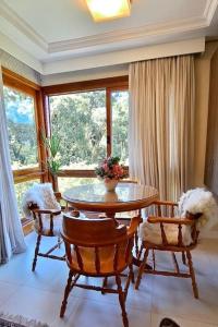 a dining room with a table and chairs and a window at Melhor localização de Gramado in Gramado