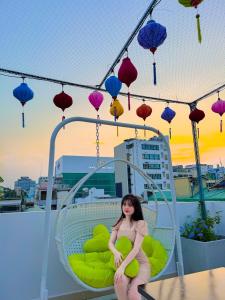 a woman is sitting on a chair with lanterns at Saigon Hotel & Apartment in Ho Chi Minh City