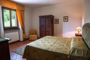 1 dormitorio con cama, ventana y silla en Großes Ferienhaus in Lonnano mit Schönem Garten, en Pratovecchio