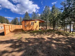 a small wooden cabin in a field with trees at Rustic 1 bd 1 ba Cabin at New Waitts Lake Resort in Valley