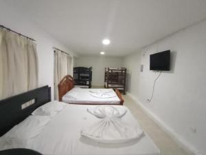 two beds in a room with a tv on the wall at HOTEL VISTA AL MAR habitacion para 6 personas in Rodadero