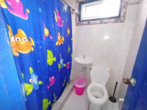 a bathroom with a toilet and a blue shower curtain at HOTEL VISTA AL MAR habitacion para 6 personas in Rodadero