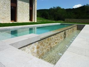- une piscine avec un mur en pierre à côté d'une maison dans l'établissement Ferienhaus in Rotecastello mit Großem Garten, à San Venanzo