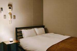 a bedroom with a bed with white sheets and a side table at Shibuya Apartment Room Dogenzaka in Tokyo